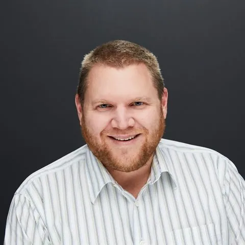 Headshot of Nick Strupp, smiling, in a striped collared shirt.